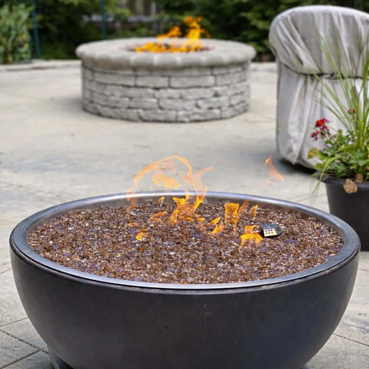 HPC Fire Inspired Hearth Products walnut penta torpedo fire bowl in a backyard patio setting, filled with amber fire glass and lit flames, placed on stone pavers with outdoor seating nearby, creating a cozy residential fire feature.