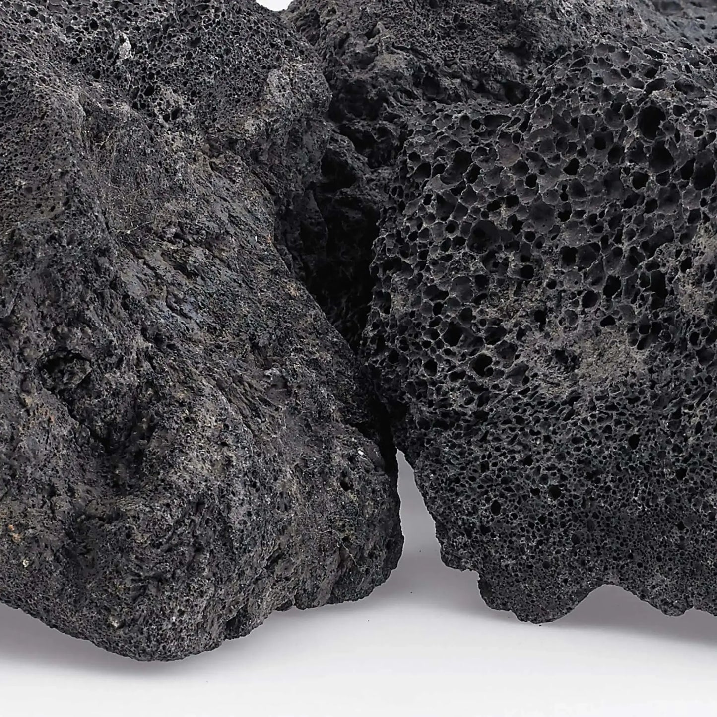 Close-up view of extra extra large lava rock revealing dense volcanic vesicles, rough texture, and natural dark gray coloration with subtle mineral variations.