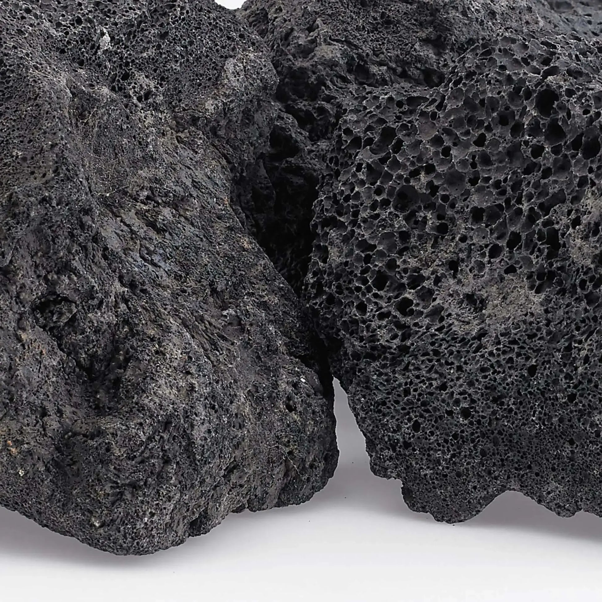 Close-up view of extra extra large lava rock revealing dense volcanic vesicles, rough texture, and natural dark gray coloration with subtle mineral variations.