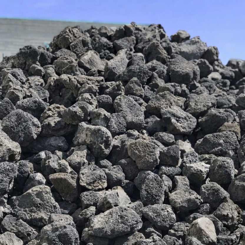 Large mound of extra extra large lava rocks stacked outdoors, showing varied organic shapes and coarse volcanic texture ideal for large-scale fire features or landscaping.