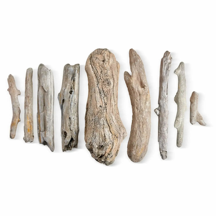Nine individual driftwood-style ceramic gas fire pit logs laid out separately on a white background, displaying different lengths, curved branch shapes, natural cracks, and textured grain for customizable log arrangement in gas fire pits.