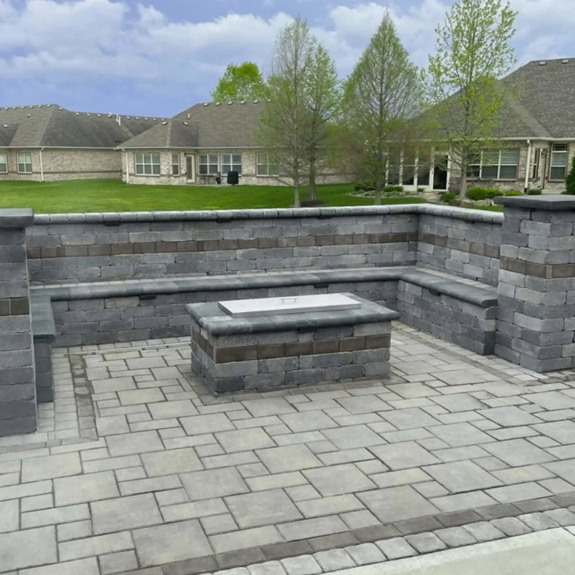 Rectangular stainless steel fire pit burner cover installed on a modern stone fire feature, offering a clean brushed finish that converts the fire pit into a usable tabletop.