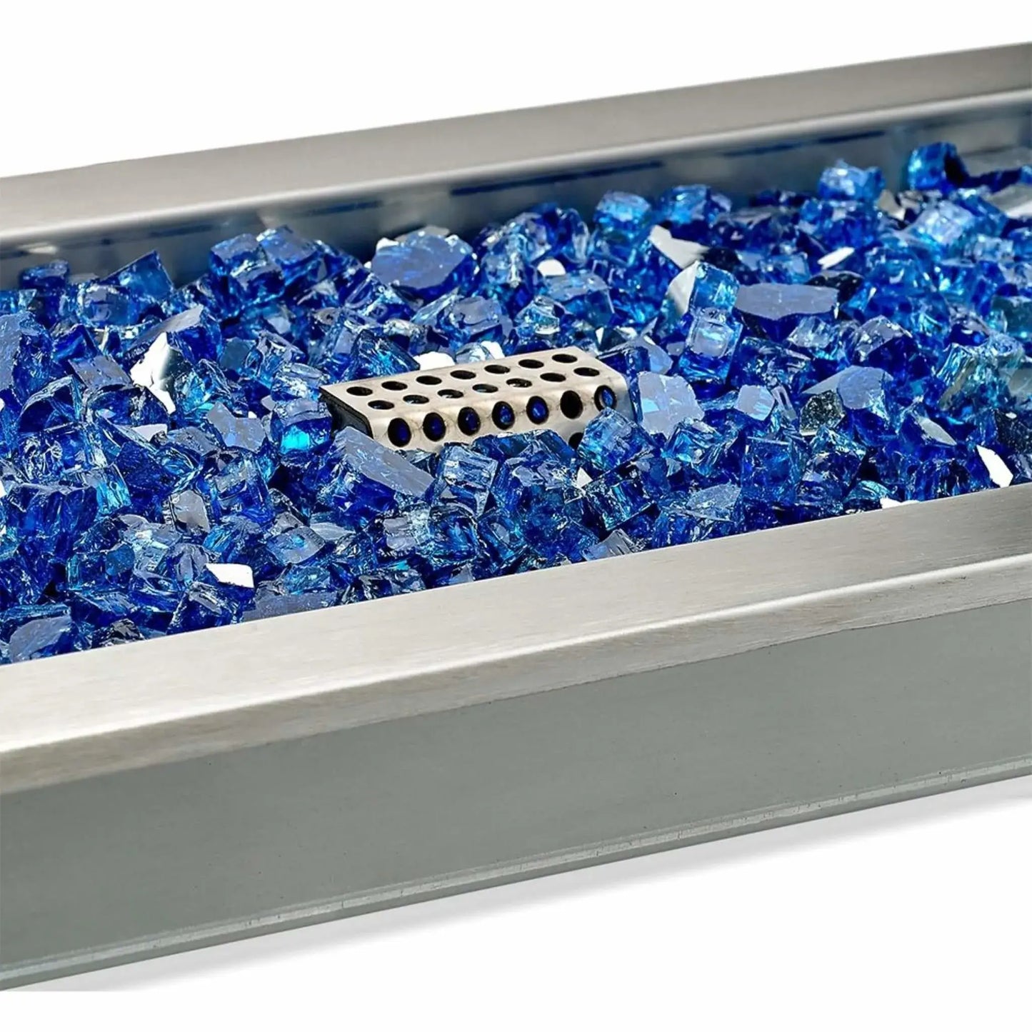 Close-up of the ignitor cage inside a stainless steel linear fire pit pan filled with blue cobalt fire glass, showing the protected ignition component surrounded by reflective tempered glass media.
