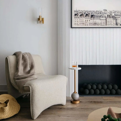 Minimal modern living room with a low, wide black fireplace insert filled with matte black fire balls, styled with a sculptural lounge chair, wall sconce, and framed artwork.