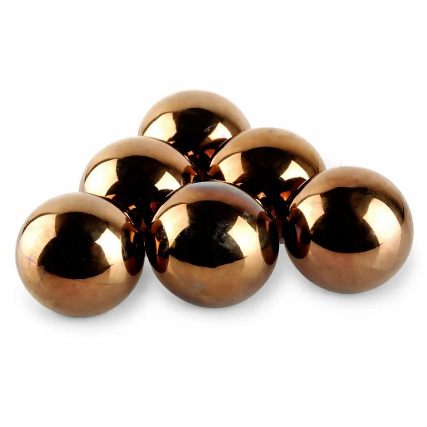 Close-up of stainless steel 4-inch fire balls exposed to flame, showing natural heat discoloration and warm bronze tones that develop during use in a gas fire feature.