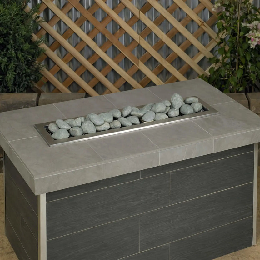 Modern rectangular gas fire table filled with Cape Gray Lite Stones by American Fire Products, shown unlit to highlight the clean stone arrangement, neutral gray color, and contemporary outdoor design.