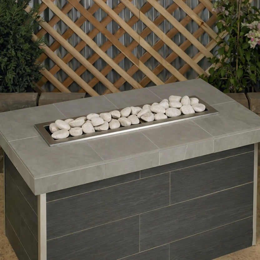 Modern rectangular gas fire table filled with Cottage White Lite Stones by American Fire Products, shown without flames to highlight the smooth stone layout and light natural color in an outdoor setting.
