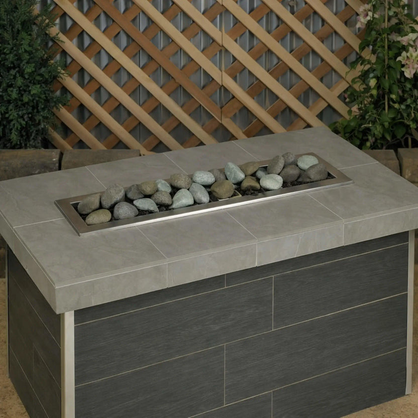 Modern rectangular gas fire table filled with Natural Lite Stones by American Fire Products, shown unlit to highlight the mixed stone colors, natural texture, and clean linear layout.