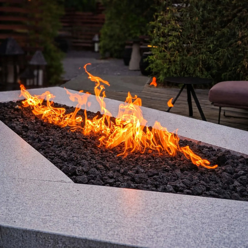 Custom linear rectangular fire pit burner bed filled with medium black lava rock, creating a long ribbon flame feature in a sleek outdoor patio design.
