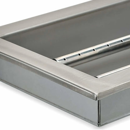 Angled close-up of a stainless steel fire pit pan showing the interior burner rail, reinforced pan walls, and smooth brushed steel surface used in outdoor fire pit systems.