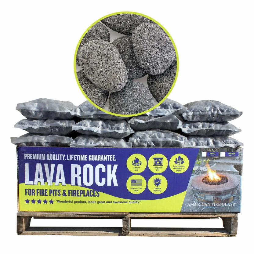 Pallet display of bagged American Fire Products rolled lava rock for fire pits and fireplaces, stacked in clear plastic bags with branded signage highlighting premium quality, lifetime guarantee, and made in the USA.