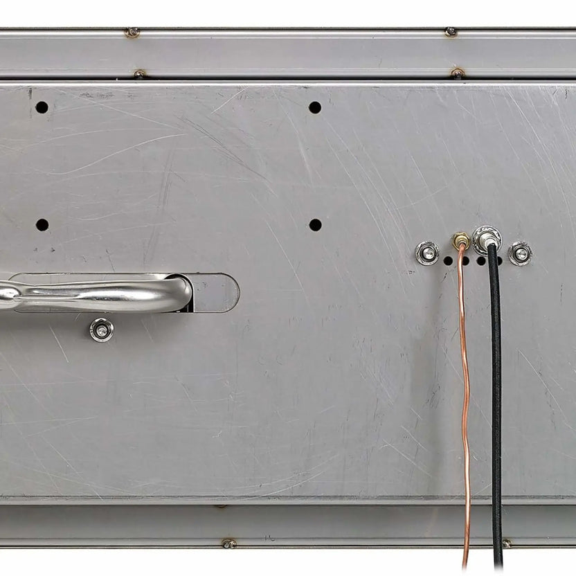 Bottom view of a stainless steel linear drop-in fire pit pan showing the underside construction, mounting hardware points, and gas and ignition line connections. The image highlights the reinforced stainless steel base, pre-drilled access holes, and wiring ports used for CSA-certified installation in outdoor fire features.