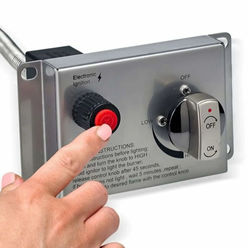 Close-up image of a stainless steel fire pit control panel with a hand pressing the red electronic ignition button next to the gas control knob. The panel displays labeled ignition and flame adjustment settings, demonstrating how the CSA-certified fire feature is manually ignited and controlled for safe outdoor operation.