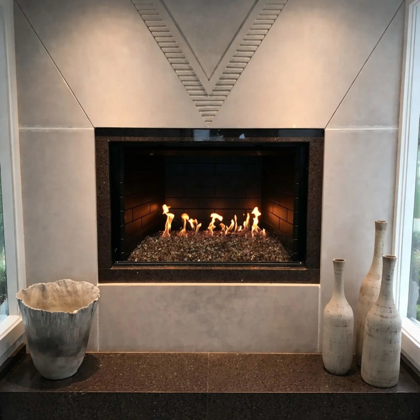 Contemporary indoor fireplace installation showcasing a stainless steel H-burner with mixed fire glass media, framed by a modern surround and decorative accents, delivering even flame distribution and a warm ambient glow.