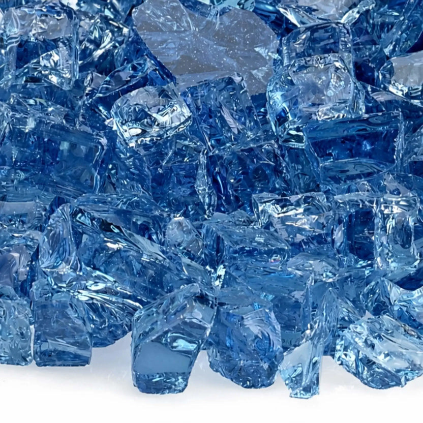 Close-up view of American Fire Products 1/2 inch Classic Non-Reflective Pacific Blue tempered fire glass, showcasing a mix of deep ocean blue and lighter aqua tones with smooth, tumbled edges and translucent depth designed to enhance flame movement in modern gas fire pits.