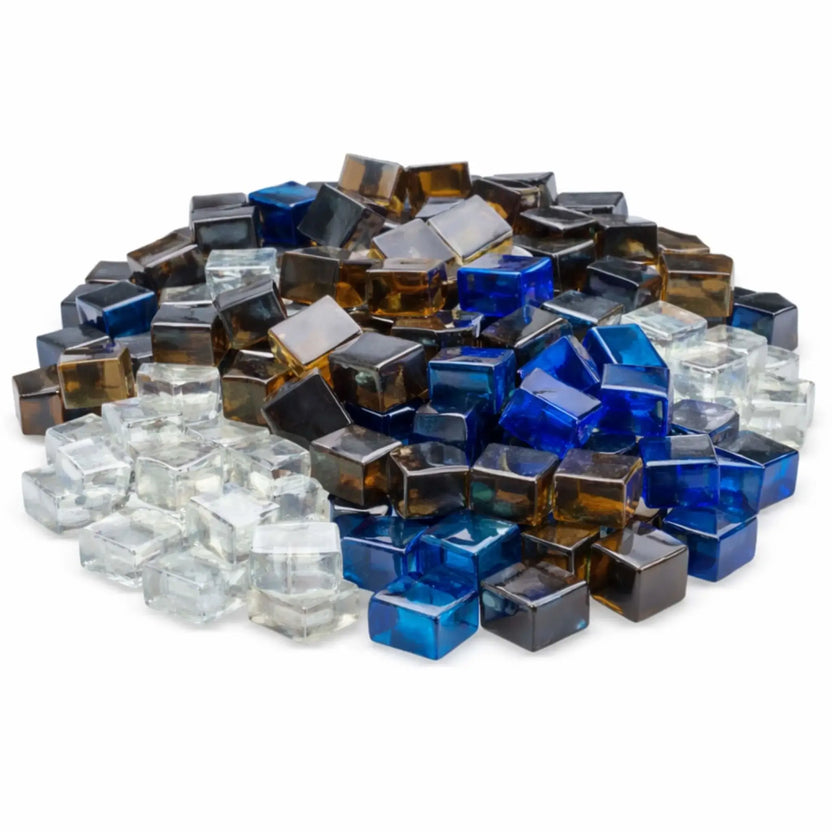 A close-up studio image of American Fire Products tempered fire glass cubes in a half-inch Luster 2.0 finish, shown in a mixed assortment of black, bronze, copper, Pacific blue, starfire clear, and white. The reflective glass cubes are stacked in a loose pile against a clean white background, highlighting their glossy, faceted surfaces and rich, jewel-toned colors designed for use in gas fire pits and fireplaces.