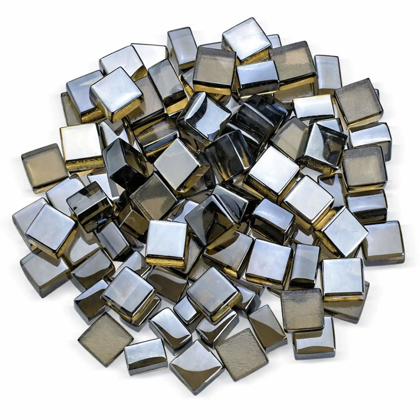 Top-down studio view of bronze Luster 2.0 half-inch tempered fire glass cubes arranged in a loose circular pile on a white background. The reflective surfaces show a smoky, metallic bronze tone with subtle gold undertones, highlighting the polished edges and dimensional shape designed for gas fire pits and fireplaces.