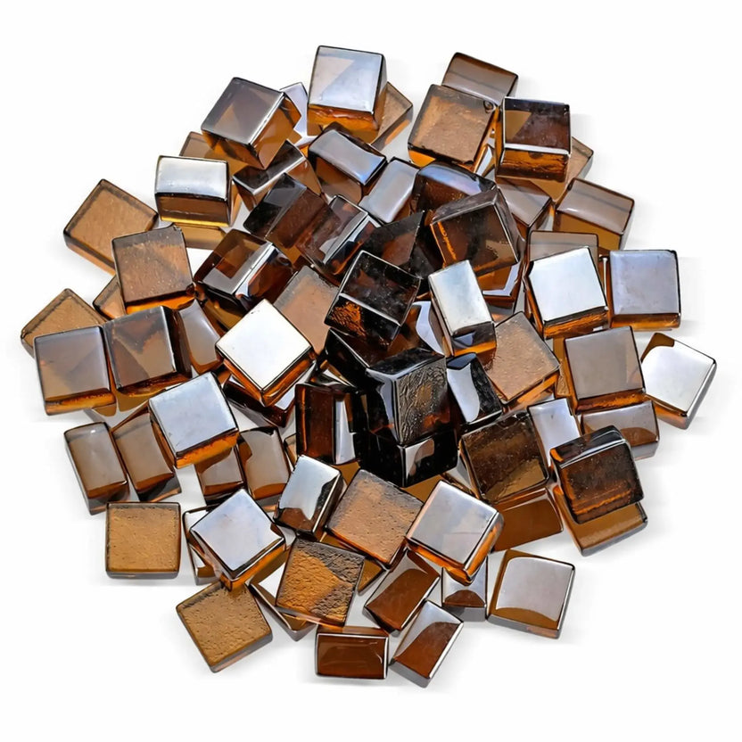 Overhead studio shot of copper Luster 2.0 tempered fire glass cubes arranged in a circular pile on a white surface. The translucent amber and bronze tones are clearly visible from above, showcasing the depth, shine, and uniform half-inch cube shape.