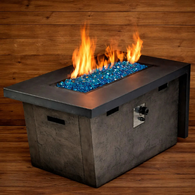 Linear outdoor gas fire feature filled with Pacific blue Luster 2.0 fire glass cubes, set against a scenic overlook with a blurred city and hillside backdrop. The vibrant blue glass contrasts beautifully with the sleek metal fire pit surround, creating a striking contemporary design element.