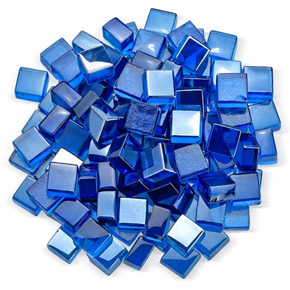 Overhead studio shot of Pacific blue Luster 2.0 half-inch tempered fire glass cubes arranged in a circular pile on a white background. The polished, translucent blue cubes reflect light from multiple angles, showcasing their smooth edges and jewel-like finish.