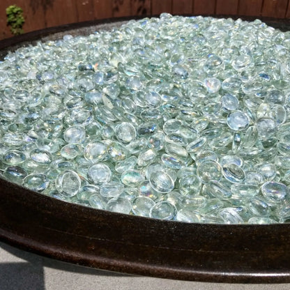 Round fire bowl fully filled with clear tempered glass luster beads, their polished surfaces catching the light and creating a soft, crystal-like shimmer.
