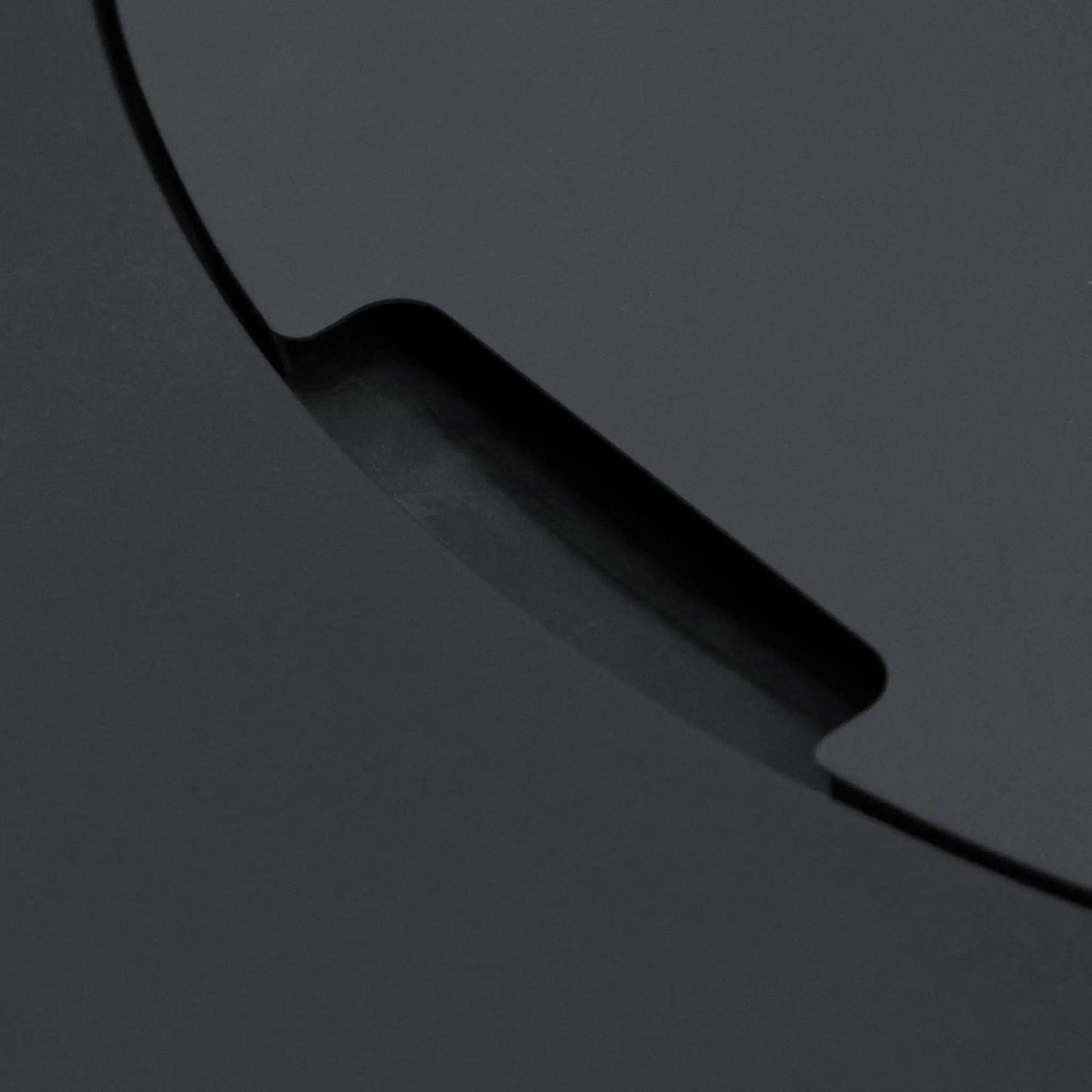 Close-up detail of the recessed handle cutout on the burner cover of the Elementi Art of Living Pacaya Dark Grey fire pit table. The image highlights the integrated lifting notch built into the round lid, emphasizing the concealed design and premium craftsmanship of the hidden propane GFRC concrete outdoor fire pit.