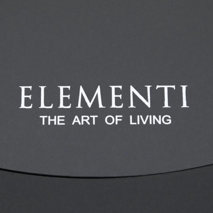 Close-up of the Elementi Art of Living branding printed on the removable burner cover of the Pacaya Dark Grey round fire pit table. The image showcases the clean finish of the GFRC concrete surface and reinforces the premium design details associated with this hidden propane outdoor fire feature.