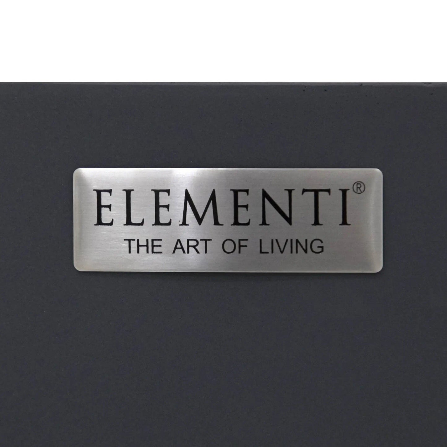 Close-up image of the brushed metal Elementi Art of Living nameplate attached to the Pacaya Dark Grey round fire pit table. The premium badge contrasts against the dark grey GFRC concrete finish, highlighting the branding and refined design details of this hidden propane outdoor fire pit table.