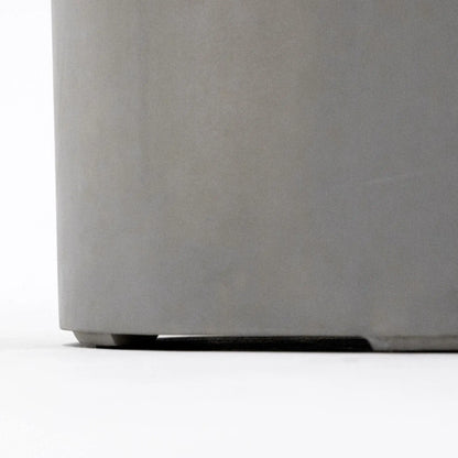 Close-up detail of the lower base section of the Elementi Art of Living Pacaya Light Grey round GFRC concrete fire pit table. The image highlights the elevated support feet beneath the cylindrical concrete body, showcasing stability, airflow clearance, and the durable construction details that contribute to the fire pit table’s premium outdoor performance.