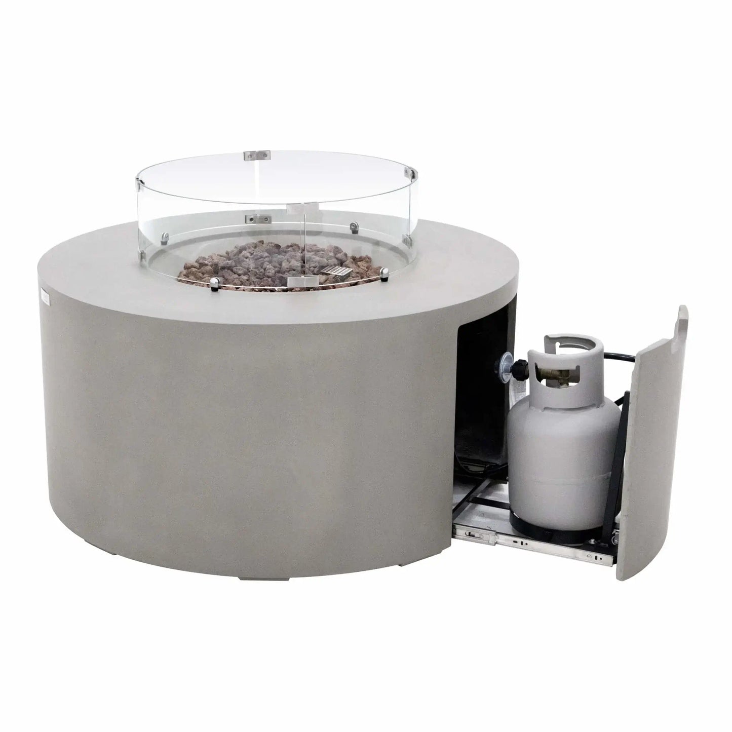 Elementi Art of Living Pacaya Light Grey GFRC concrete fire pit table shown with the hidden propane drawer extended. The image reveals the concealed propane tank storage system mounted on a sliding tray beneath the round fire table, while the glass wind guard and lava rock burner area remain visible above, demonstrating the clean hidden propane design and easy fuel access.