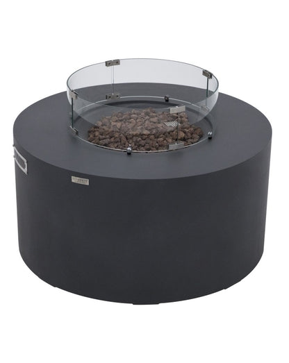 Elementi Pacaya Round Fire Pit Table in dark grey GFRC concrete, featuring a tempered glass wind guard and natural lava rock media. This modern fire pit boasts a hidden propane tank compartment for a sleek aesthetic, while the wind guard enhances flame stability and safety. A perfect blend of durability and contemporary design, making it an ideal outdoor focal point for stylish gatherings.