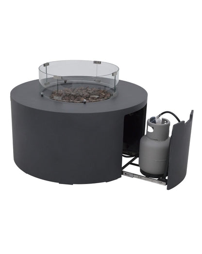 Elementi Pacaya Round Fire Pit Table in dark grey GFRC concrete, featuring a glass wind guard, natural lava rock media, and a hidden propane tank compartment with a pull-out drawer. Designed for both elegance and convenience, this modern fire pit seamlessly conceals the propane tank while providing easy access. The glass wind guard enhances flame stability, making this fire pit a perfect centerpiece for contemporary outdoor spaces.