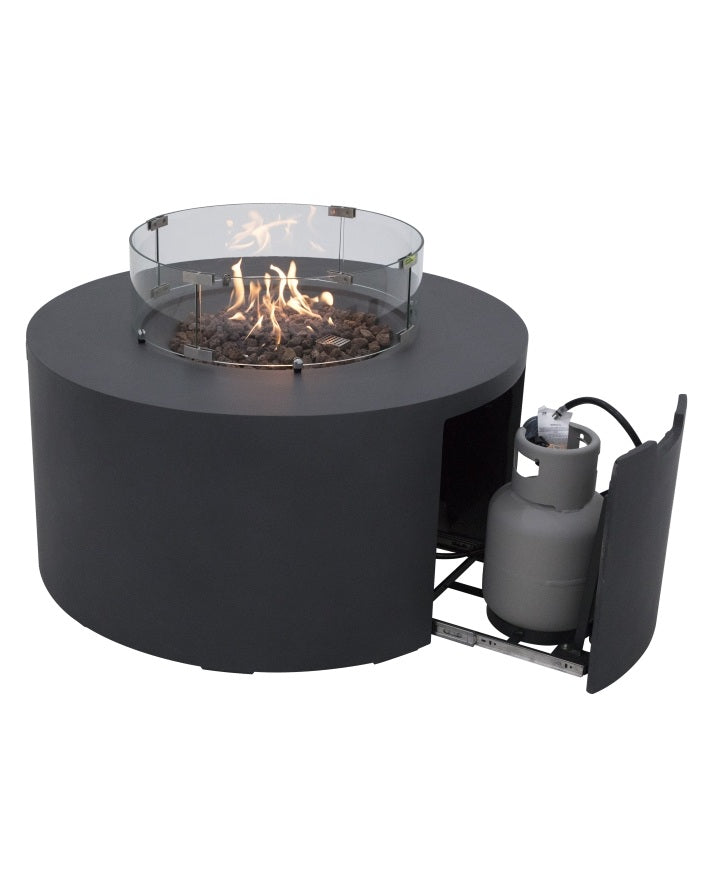 Elementi Pacaya Round Fire Pit Table in dark grey GFRC concrete, featuring a vibrant flame over natural lava rocks, a tempered glass wind guard, and a hidden propane tank with a pull-out drawer. Designed for both functionality and elegance, this modern fire pit offers seamless propane access while enhancing outdoor spaces with warmth, ambiance, and wind protection—perfect for stylish patios and backyard gatherings.