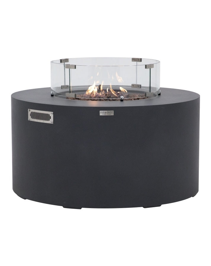 Elementi Pacaya Round Fire Pit Table in dark grey GFRC concrete, featuring a mesmerizing flame over natural lava rocks and a tempered glass wind guard. Designed with a hidden propane tank for a sleek, modern aesthetic, this luxury fire pit enhances outdoor spaces with warmth and ambiance while ensuring safety and wind protection. A perfect blend of contemporary design and functionality for stylish patios and backyards.