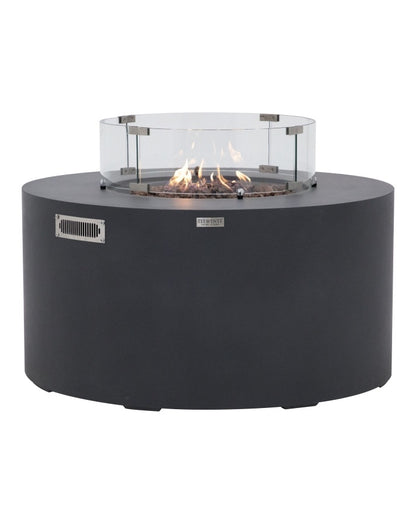 Elementi Pacaya Round Fire Pit Table in dark grey GFRC concrete, featuring a mesmerizing flame over natural lava rocks and a tempered glass wind guard. Designed with a hidden propane tank for a sleek, modern aesthetic, this luxury fire pit enhances outdoor spaces with warmth and ambiance while ensuring safety and wind protection. A perfect blend of contemporary design and functionality for stylish patios and backyards.