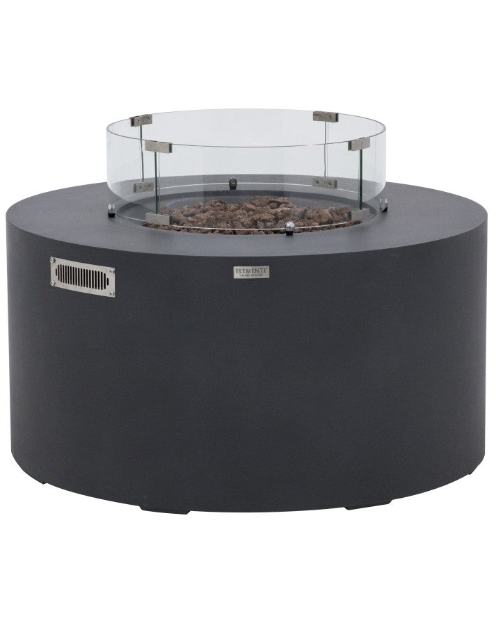 Elementi Pacaya Round Fire Pit Table in dark grey GFRC concrete, featuring a sleek glass wind guard and natural lava rock media. Designed with a hidden propane tank for a seamless look, this modern fire pit combines durability and elegance. The glass wind guard enhances flame stability while adding a contemporary touch, making it an ideal outdoor centerpiece for stylish gatherings.
