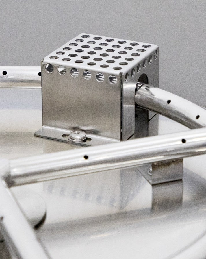 Close-up of the stainless steel burner system in the Elementi Pacaya Round Hidden Propane Tank Fire Pit Table. This precision-engineered component ensures efficient and consistent flames, delivering both durability and optimal performance for outdoor heating and ambiance.