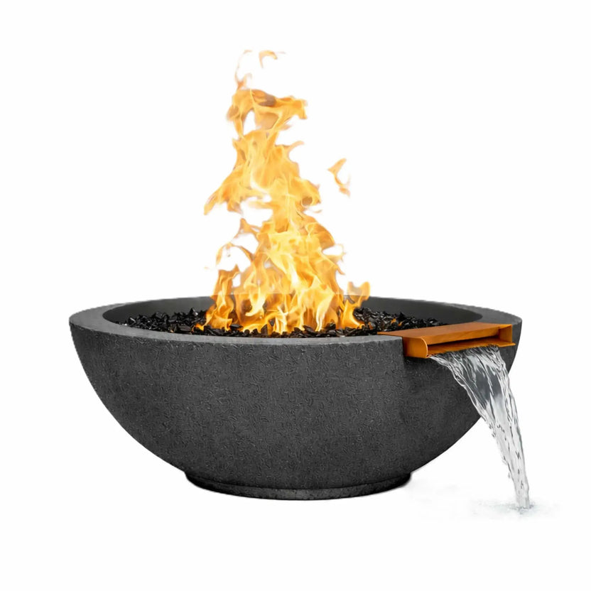 Black round concrete fire and water bowl with a dramatic gas flame rising above black fire media, paired with a steady stream of water flowing from a bronze spillway, isolated on a white background for product detail clarity.