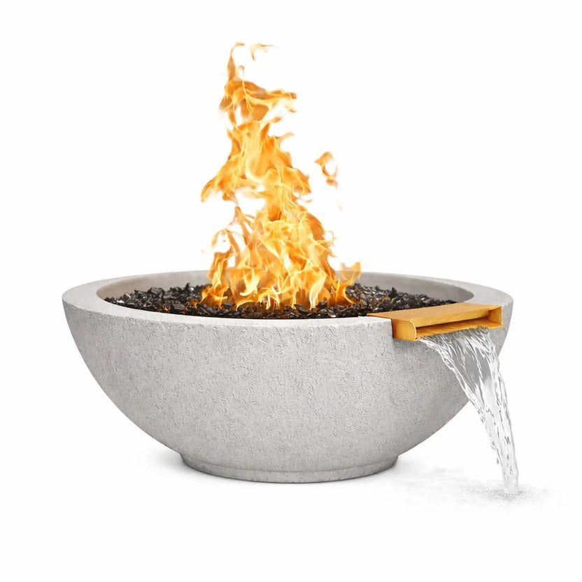 Round gray concrete fire and water bowl featuring a tall gas flame burning over black fire glass, with water flowing from an integrated bronze spillway, shown against a white background to highlight the bowl’s texture and fire-and-water design.