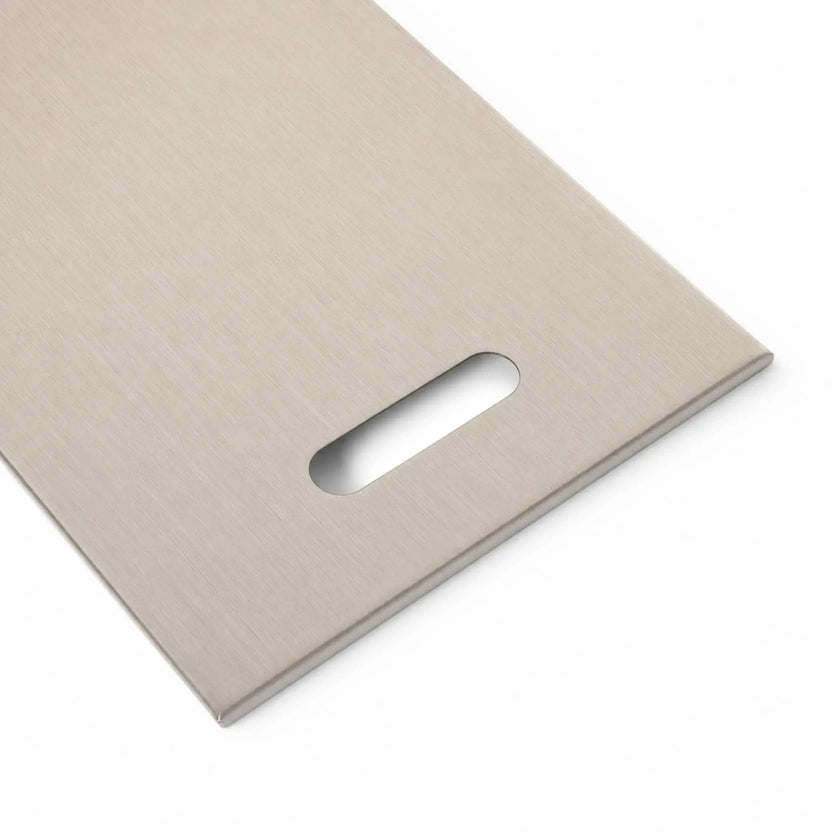 Close-up of the right handle on the Flame Havens Refuge Series 33 x 11-inch rectangular stainless steel burner cover. The angled view shows the elongated hand opening, subtly brushed metal texture, smooth finished edge, and sturdy low-profile construction on a white background.