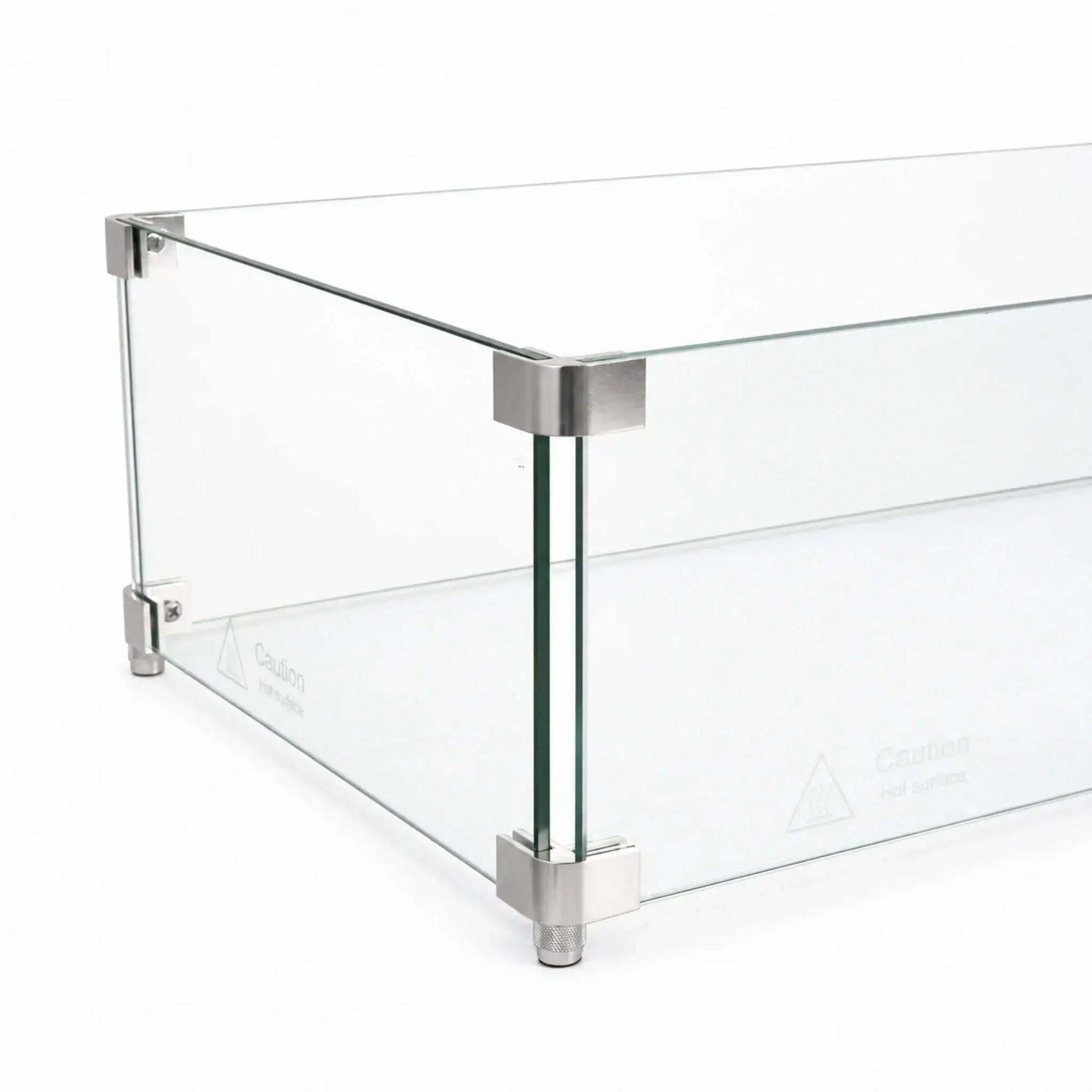 Close-up perspective of the Flame Havens Refuge Series 36 x 14 x 7-inch rectangular tempered glass wind guard shield, showing clear panels joined at the corners with brushed silver metal hardware. The image highlights the upper connectors, lower brackets, adjustable feet, polished edges, and hot-surface safety markings.