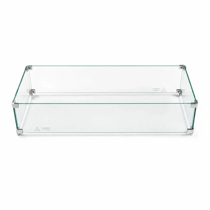 Fully assembled Flame Havens Refuge Series 36 x 14 x 7-inch rectangular tempered glass wind guard shield shown against a white background. Four clear glass panels form a low-profile enclosure joined by silver corner brackets and support feet, with visible “Caution Hot surface” markings along the lower edges.