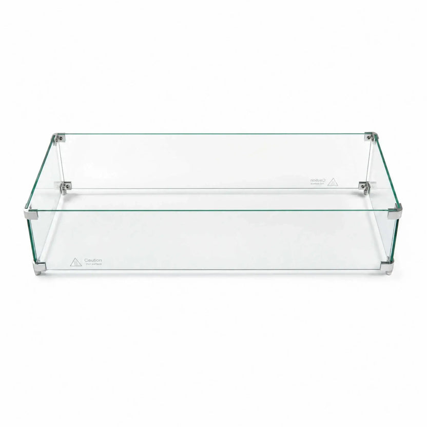 Fully assembled Flame Havens Refuge Series 36 x 14 x 7-inch rectangular tempered glass wind guard shield shown against a white background. Four clear glass panels form a low-profile enclosure joined by silver corner brackets and support feet, with visible “Caution Hot surface” markings along the lower edges.