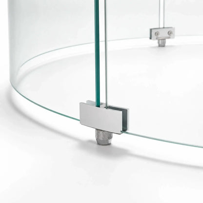 Close-up of a support foot on the Flame Havens Refuge Series 28-inch round by 7-inch-tall tempered glass wind guard shield. The silver metal bracket secures two curved glass panels while a knurled adjustable foot supports the assembly above the fire pit surface.
