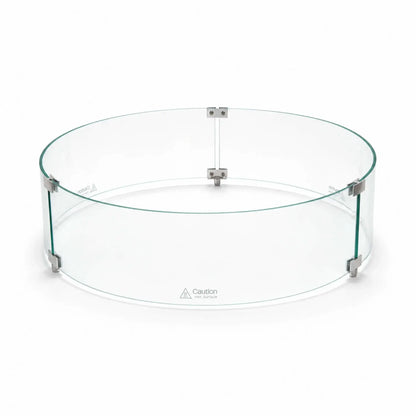 Angled main view of the assembled Flame Havens Refuge Series tempered glass wind guard shield, measuring 28 inches in diameter by 7 inches tall. Three curved clear glass panels form a complete circle, joined by silver clamps and raised support feet, with “Caution Hot Surface” warnings near the bottom.
