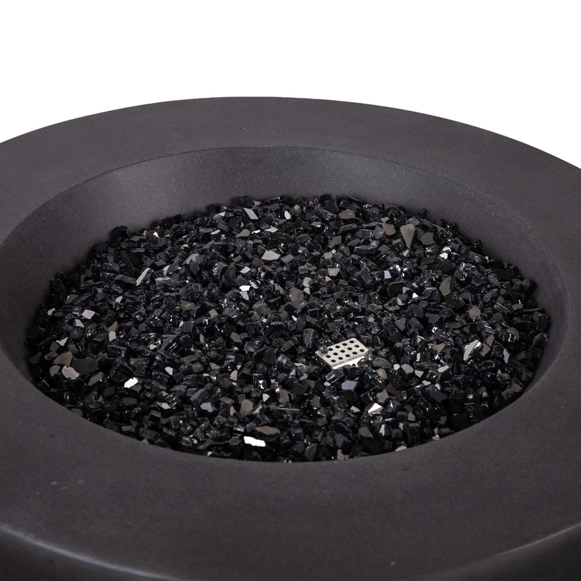 Close-up view of the Flame Havens Refuge Series 36-inch Round Natural Gas GFRC Concrete Fire Pit in Black, showcasing the premium black reflective fire glass evenly covering the stainless steel burner system. The image highlights the smooth concrete finish, generous burner opening, and elegant round design, demonstrating the upscale appearance of the Black Fire Glass media before the fire pit is ignited.