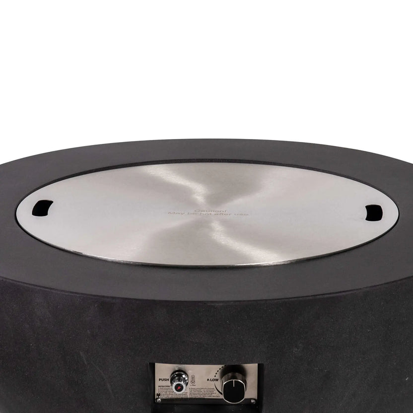 Front product image of the Flame Havens Refuge Series 36-inch Round Natural Gas GFRC Concrete Fire Pit in Black with the optional stainless steel burner cover installed. The flush-mounted cover transforms the fire pit into a functional outdoor coffee table while preserving the burner beneath and complementing the modern GFRC concrete design.