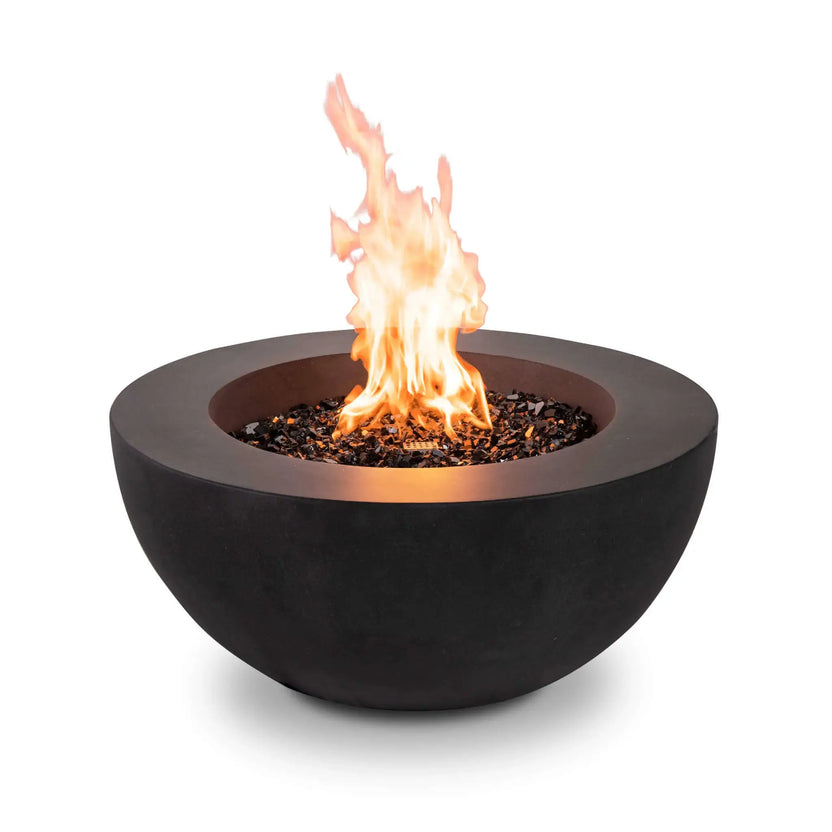 The Flame Havens Refuge Series 36-inch Round Natural Gas GFRC Concrete Fire Pit in Black burning with a vibrant natural gas flame above premium tempered black reflective fire glass. The image emphasizes the clean front profile without visible controls, showcasing the modern bowl design and warm, inviting flame presentation for luxury outdoor living.