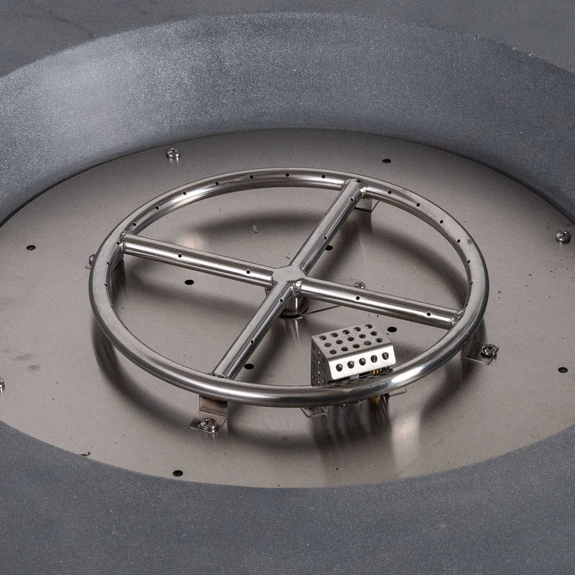 Close-up view inside the Flame Havens Refuge Series 36-inch Round Natural Gas Gray GFRC Concrete Fire Pit showing the stainless steel circular burner ring, CSA-certified ignition assembly, and precision-engineered burner components before the fire glass is installed. The image highlights the durable stainless steel construction and professional burner layout.