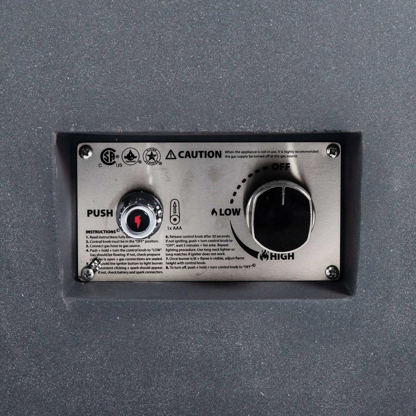 Close-up view of the Flame Havens Refuge Series 36-inch Round Natural Gas GFRC Concrete Fire Pit in Gray, highlighting the recessed stainless steel CSA-certified ignition control panel. The image clearly shows the push-button spark igniter, flame adjustment knob, OFF, LOW, and HIGH settings, and the brushed stainless control plate integrated into the textured gray GFRC concrete body for a clean, professional finish.